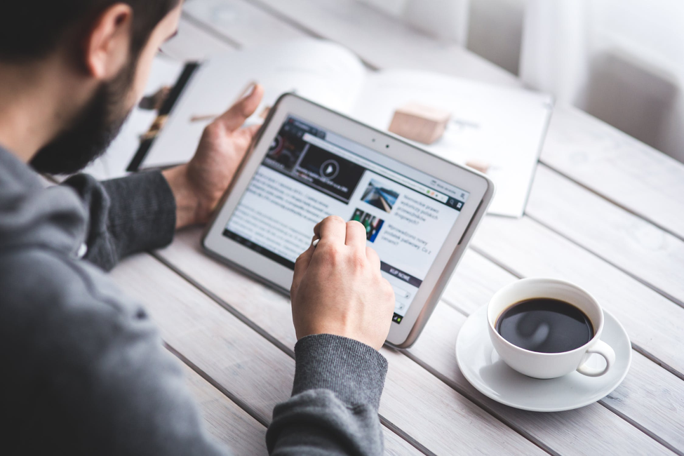 Man working on a tablet with a cup of coffee