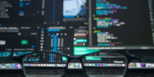 glasses in frot of code on a computer screen